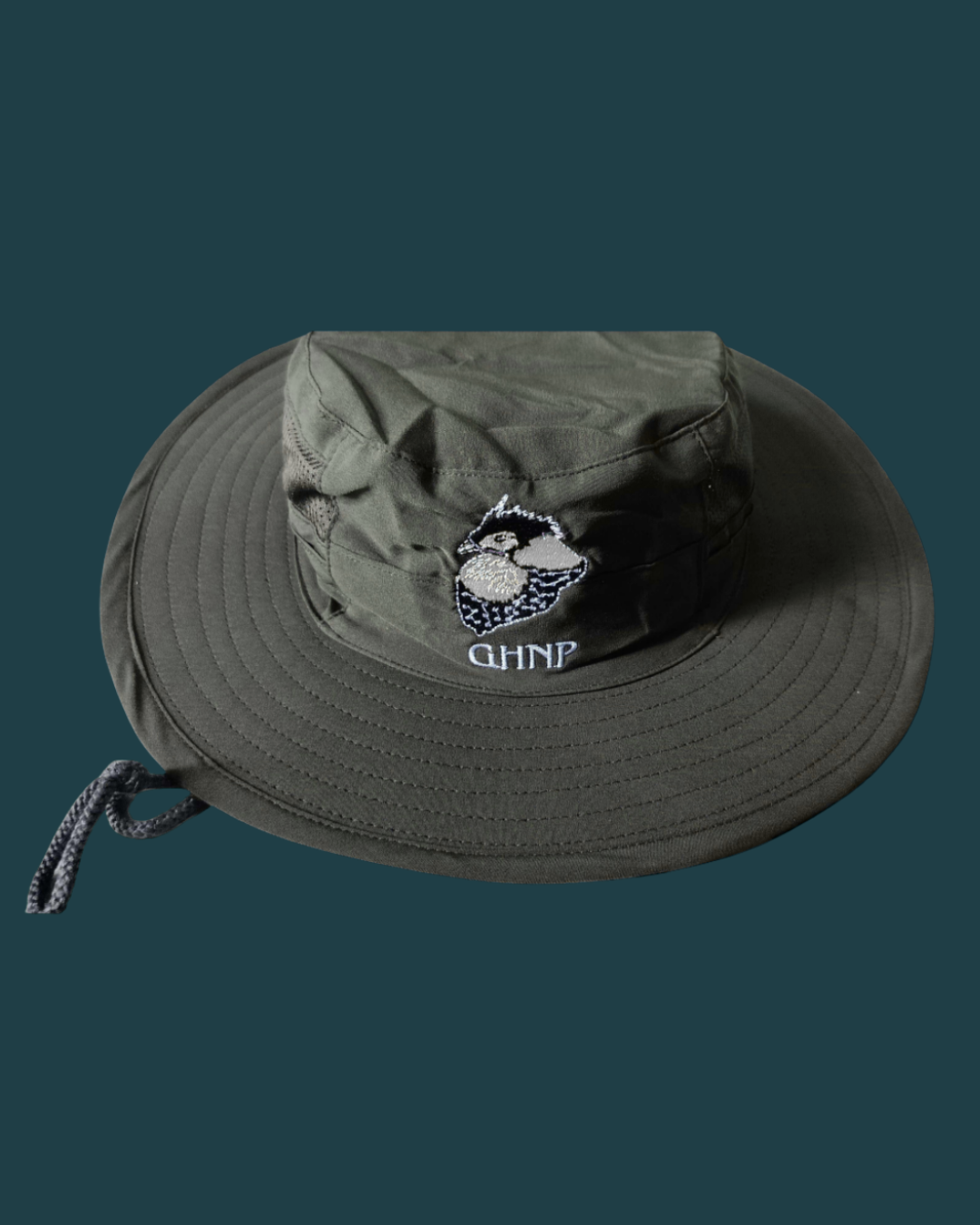 A man in a beanie and hoodie deeply praying outside in a lush green forest.